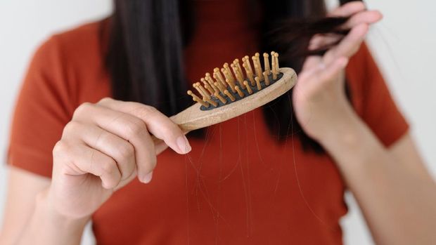 closeup woman hand holding hair fall from hairbrush