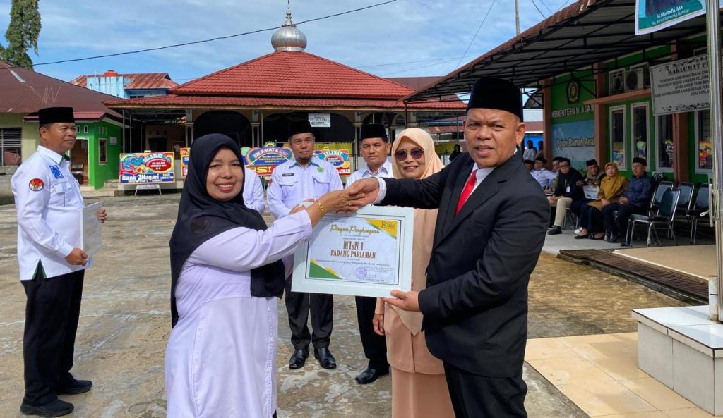 Jusma Yanti, M.Pd menerima piagam penghargaan langsung dari Kepala Kantor Kemenag Padang Pariaman, H. Syafrizal, S.Ag., MM, atas prestasi ASN Terbaik dan kinerja MTSN 1 Padang Pariaman tahun 2025. Sabtu (3/1/2025) (Fhoto : Dioni/Gonews.id)