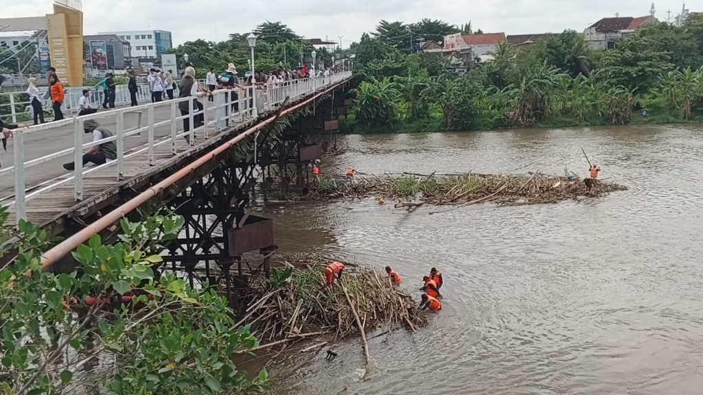 Petugas gabungan membersihkan sampah di kaki jembatan Jembatan Lama Kota Kediri atau Brug Over den Brantas te Kediri