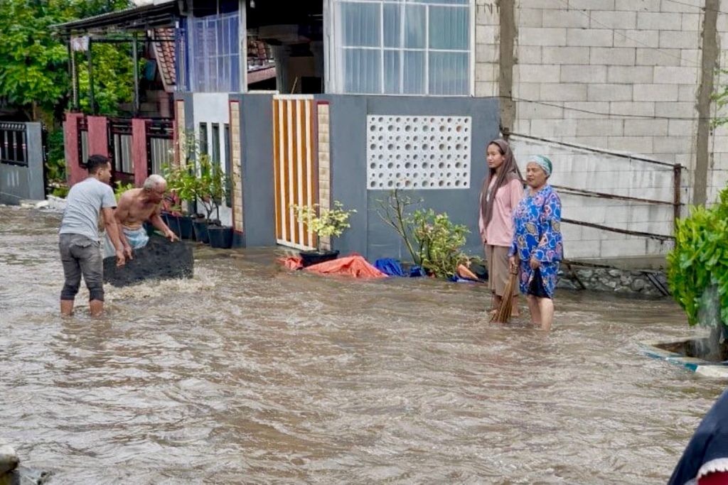 Hujan Tak Reda, Takbiran Kertosari Terancam Sepi Warga melintas di tengah aliran air setinggi lutut di Desa Kertosari, Kecamatan Kutorejo, Kabupaten Mojokerto, Jumat (20/3/2026)(Foto: Rahma)