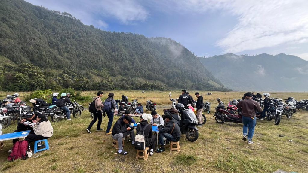 Wisatawan beristirahat sambil menikmati makanan hangat di kawasan Gunung Bromo, Senin (30/3/2026), di tengah udara dingin pegunungan.