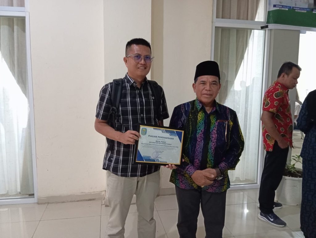 Bupati Kerinci, Monadi, menyerahkan piagam penghargaan kepada Kepala Desa Pugu, Defrizal, sebagai Desa Terbaik dalam Pelaksanaan Program Digitalisasi Desa Tahun 2026, di Kerinci, Senin (20/4/2026) (Vina/GOnews.id)