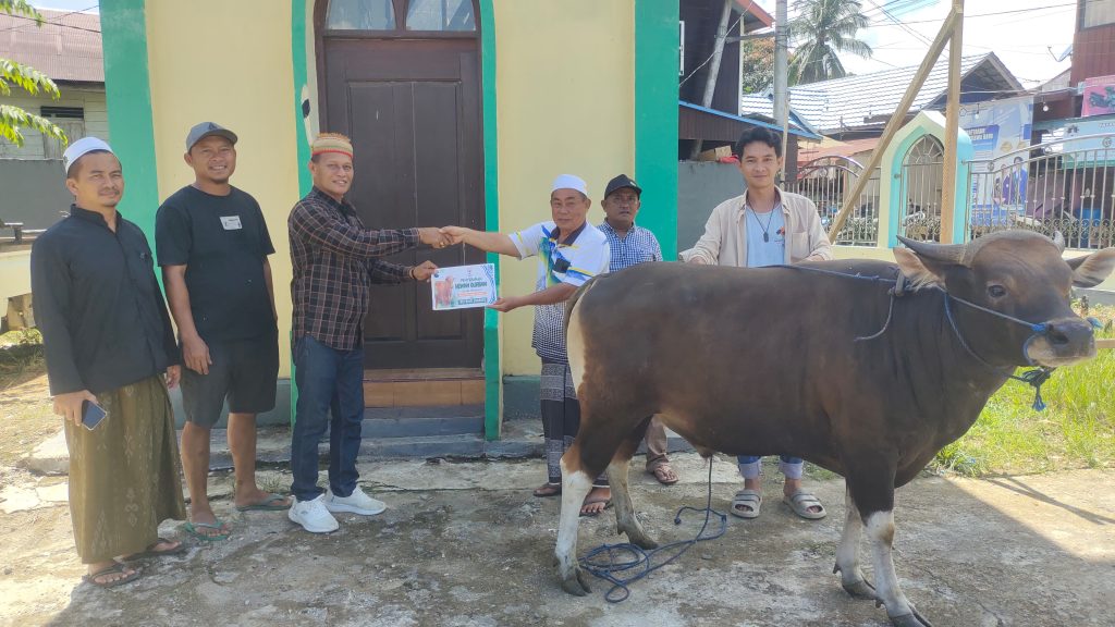 Petrus Jumriq mengenakan topi Dayak Bahau saat menyerahkan hewan kurban ke sejumlah masjid di Ujoh Bilang.
