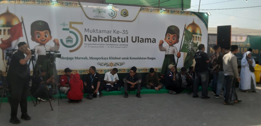 Puluhan awak media terpaksa lesehan di pelataran pintu masuk utama GSG PP Bahrul Ulum, Tambakberas, Jombang, sembari menunggu kepastian akses peliputan dari panitia PBNU.