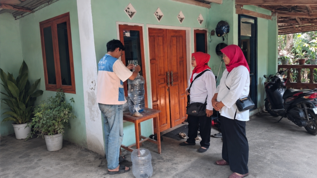Mahasiswa Kelompok 15 PKM BAHARI FPIK UB mendampingi warga dalam pemasangan instalasi akuaponik berbasis galon di rumah penerima manfaat. 