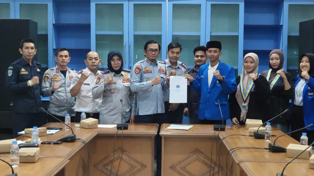 PC PMII Kutim Desak Evaluasi Transportasi Publik, Dishub Apresiasi Masukan Mahasiswa Ketua Umum PC PMII Kutai Timur, Mahrus Ali Ridho menyerahkan dokumen naskah akademik berisi tujuh rekomendasi evaluasi pelayanan transportasi publik kepada Sekretaris Dinas Perhubungan Kabupaten Kutai Timur, Masrianto Suriansyah dalam audiensi di Kantor Dishub Kutim, Sangatta, Selasa (13/10/2026). (Wahyu/GOnews.id)